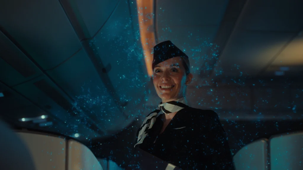 Finnair cabin crew member smiling in an aircraft cabin surrounded by drifting blue CG particles
