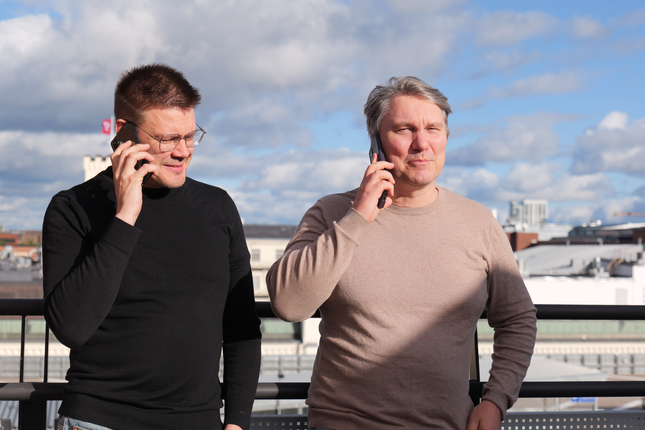Two of the Energia VFX team on the phone on a rooftop terrace, city rooftops behind them