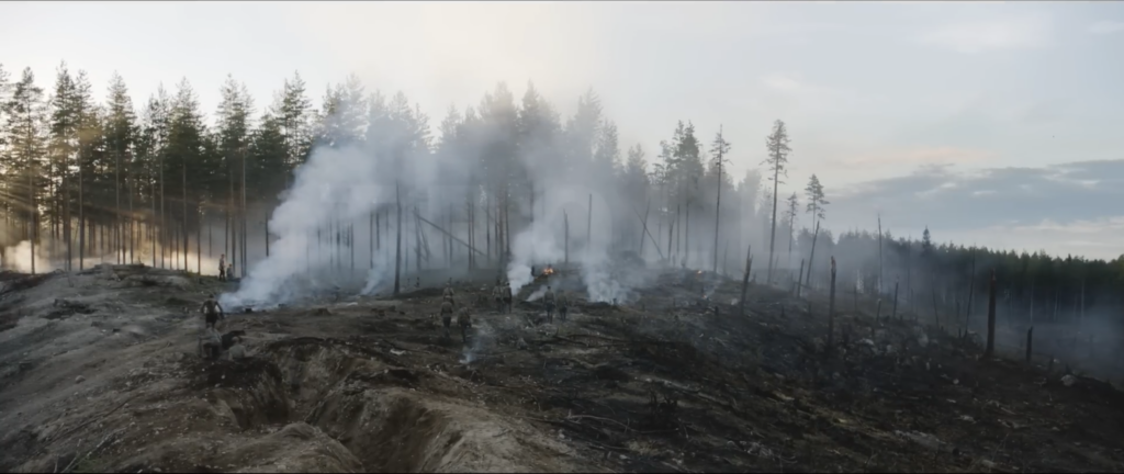 Shell-torn pine forest with smoke drifting across the treeline